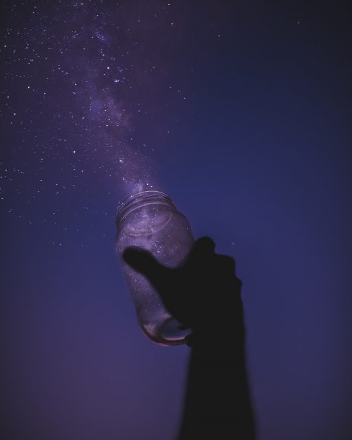 Hand holding jar looking up at night sky